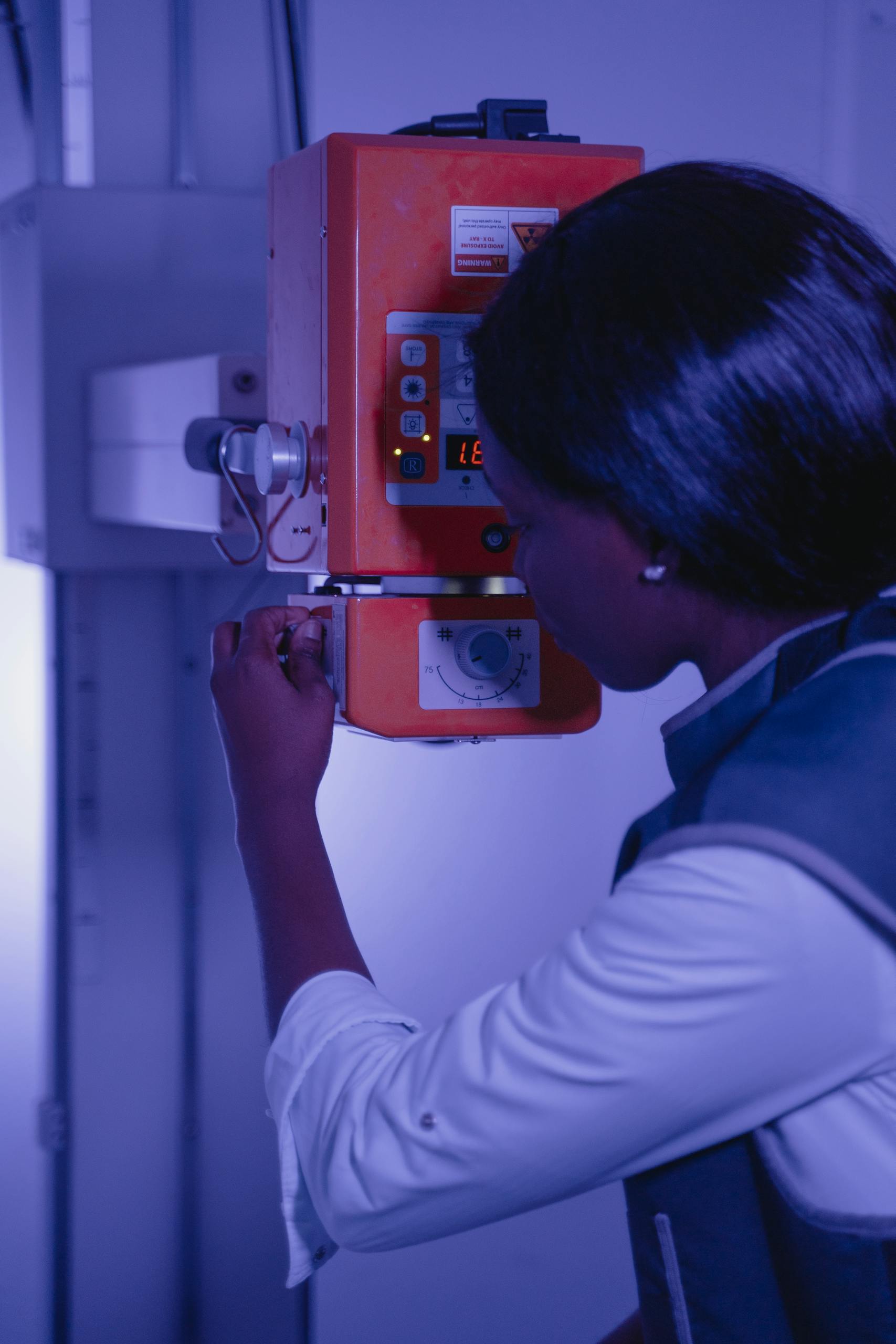 A female engineer adjusts an industrial machine's settings inside a facility.