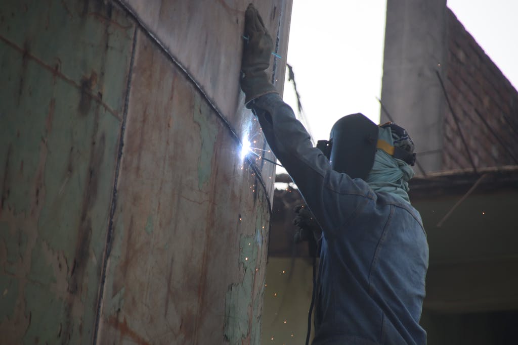 A welder works on a ship hull in Keraniganj shipyard, showcasing skilled labor in industrial settings.